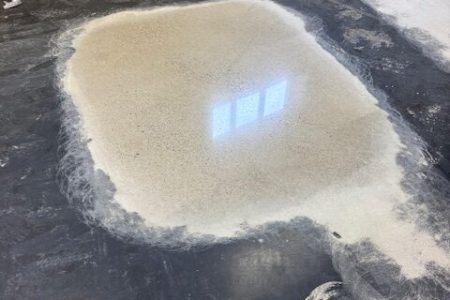 Proefvlak van een gepolijste betonvloer naast het onbehandelde vloerdeel